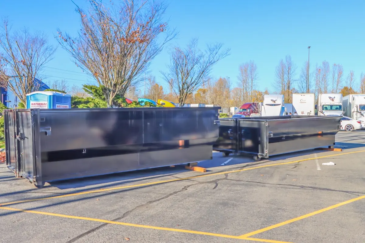 Professional dumpster rental service with roll-off container on residential driveway in Primera